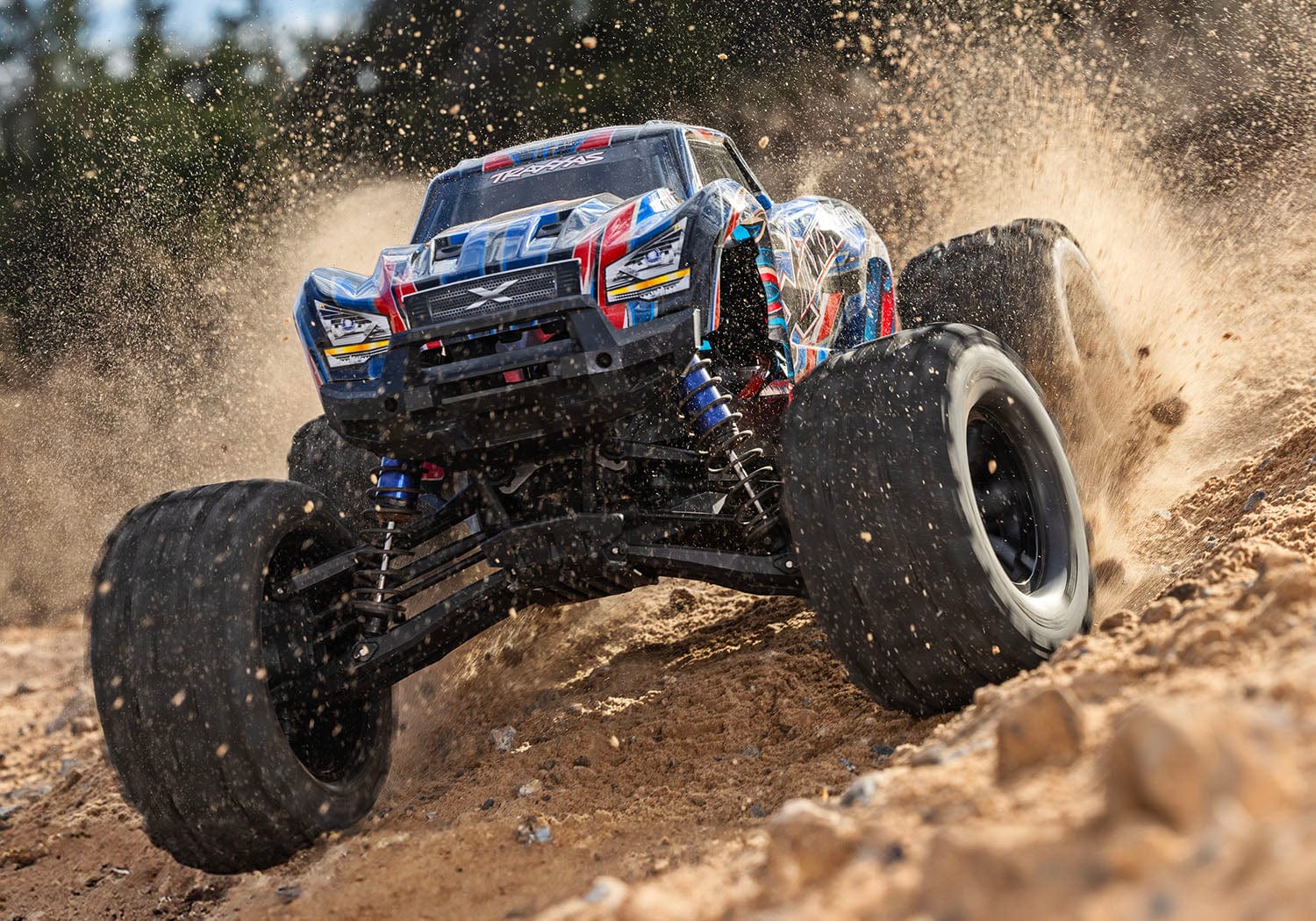 [Action] Traxxas X-Maxx Belted - mavi/kırmızı araç arazide toprak fışkırtırken