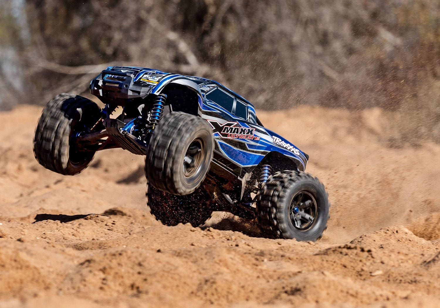 [Action] Traxxas X-Maxx - mavi araç kumlu arazide sürüş halinde