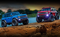 [Action] Traxxas TRX-4M Bronco - mavi ve kırmızı araçlar gün batımında kaya üzerinde