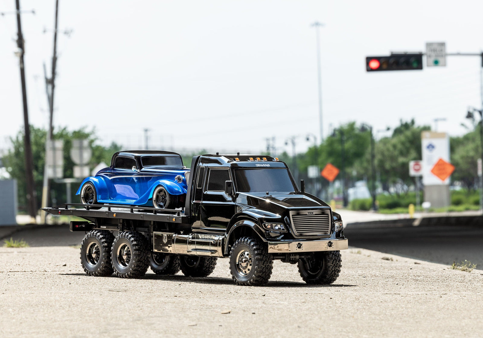 [Action] Traxxas TRX-6 Hauler - şehir sokağında 3/4 önden, mavi hot rod yüklü
