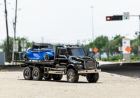 [Action] Traxxas TRX-6 Hauler - şehir sokağında 3/4 önden, mavi hot rod yüklü