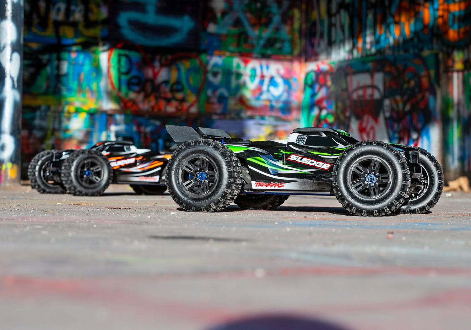 [Action] Traxxas Sledge - grafiti duvar önünde yeşil ve turuncu araçlar