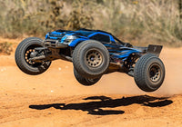 [Action] Traxxas XRT 4WD - mavi araç toprak pistte havada atlayış yapıyor