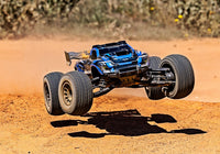 [Action] Traxxas XRT 4WD - mavi araç toprak pistte havada atlayışta