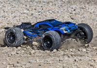 [Action] Traxxas XRT 4WD - mavi araç çakıl pistte kayarak taş püskürtüyor