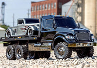 [Action] Traxxas TRX-6 Hauler - çakıl arazide 3/4 önden, gümüş alev desenli hot rod yüklü